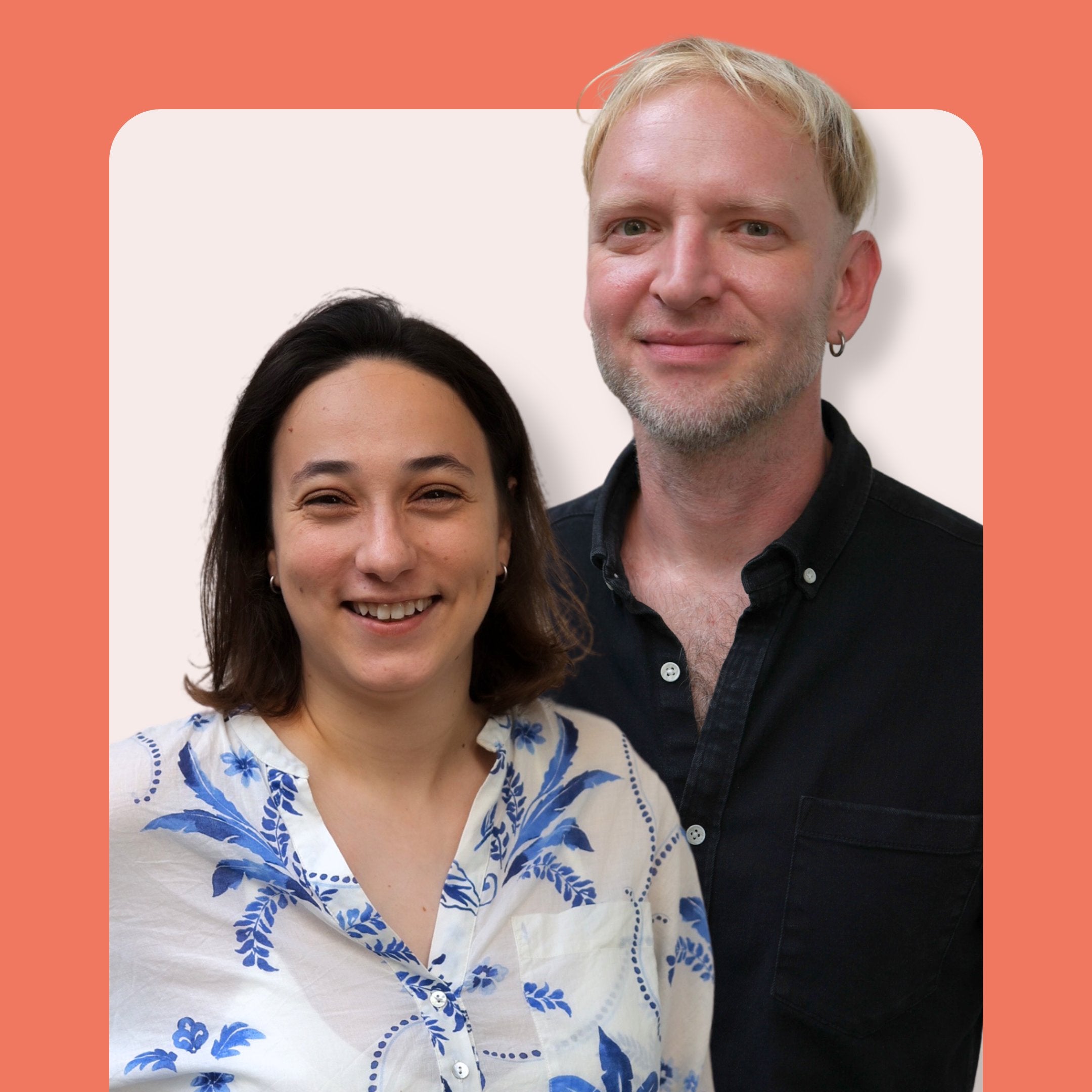 Two people, one with short dark hair in a white floral shirt and another with short blond hair in a black shirt, smiling and standing together against a peach and cream background.