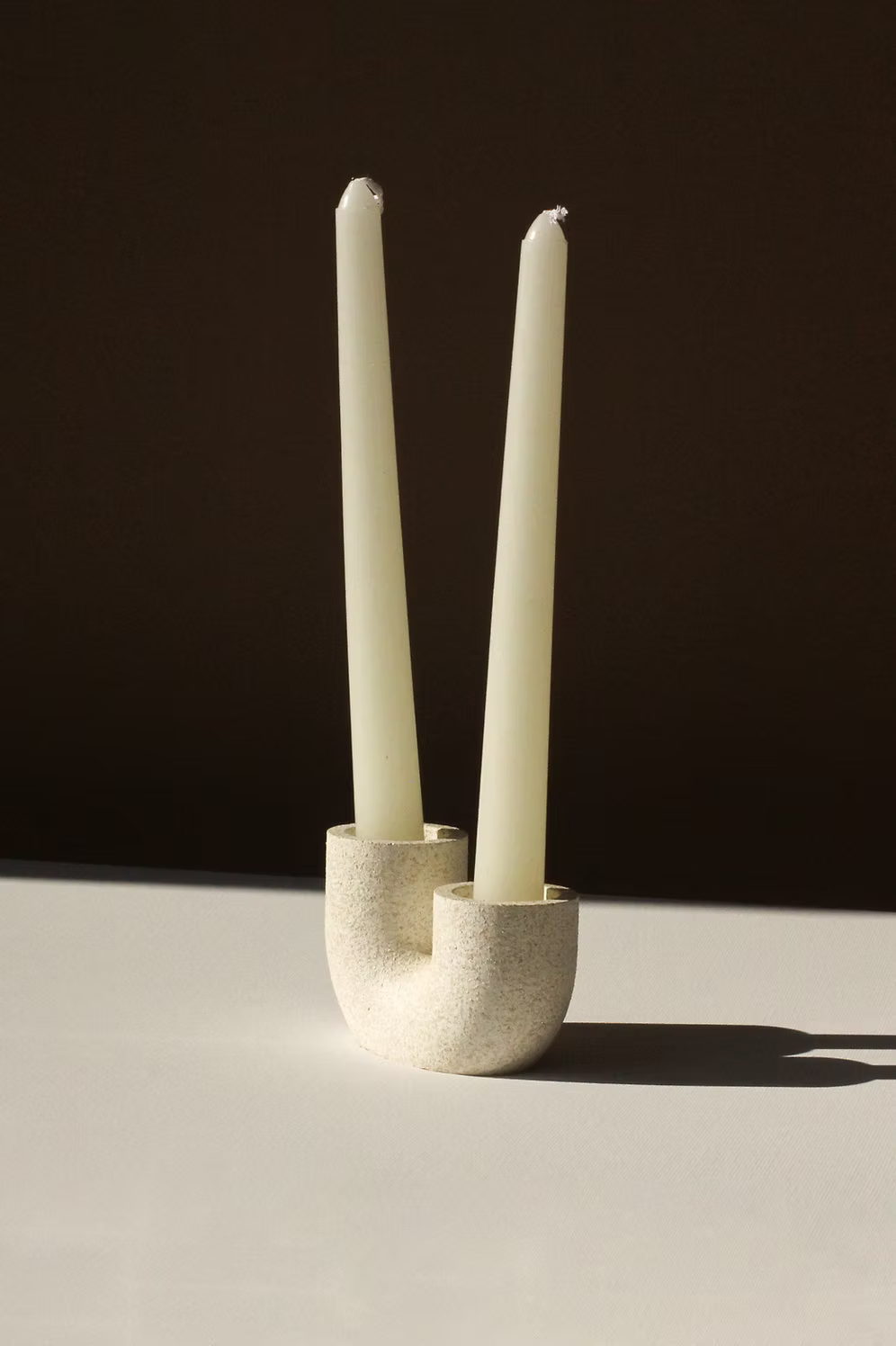 Minimalist white concrete candle holder with semicircle design and matching tall candles