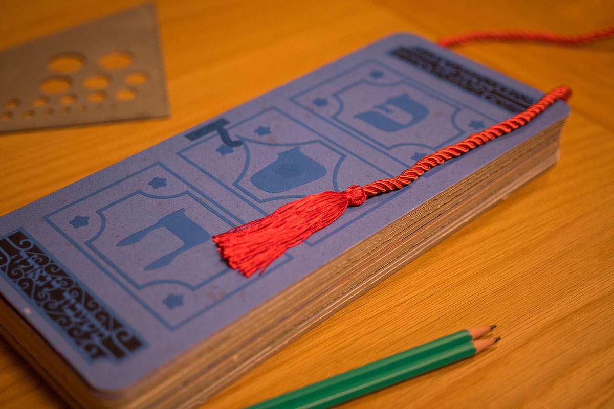 The Recreated Haggadah with interactive cards and red tassel on a wooden table.