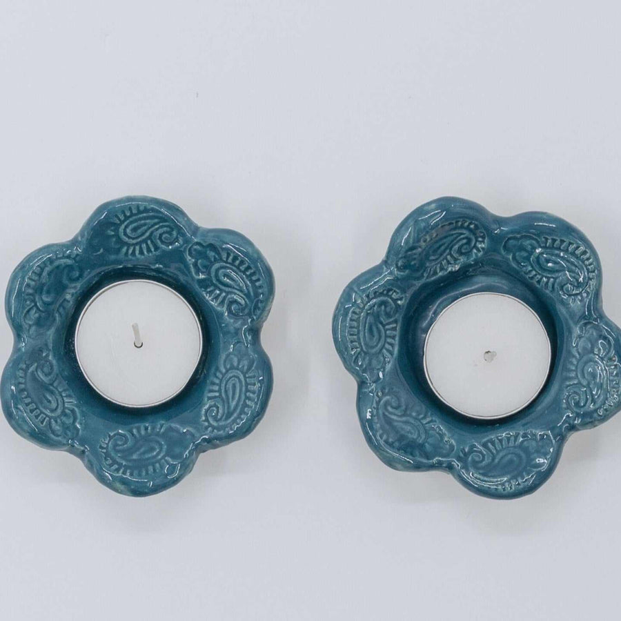 ADI Standard Shabbat Candleholders, a pair of teal ceramic flower-shaped holders with raised swirling patterns and white candles.