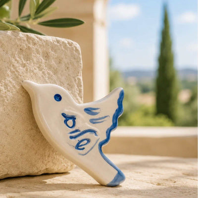 ADI Shalom Dove Magnet, cream ceramic dove with blue Hebrew lettering, blue eye, and hand-painted feather details.