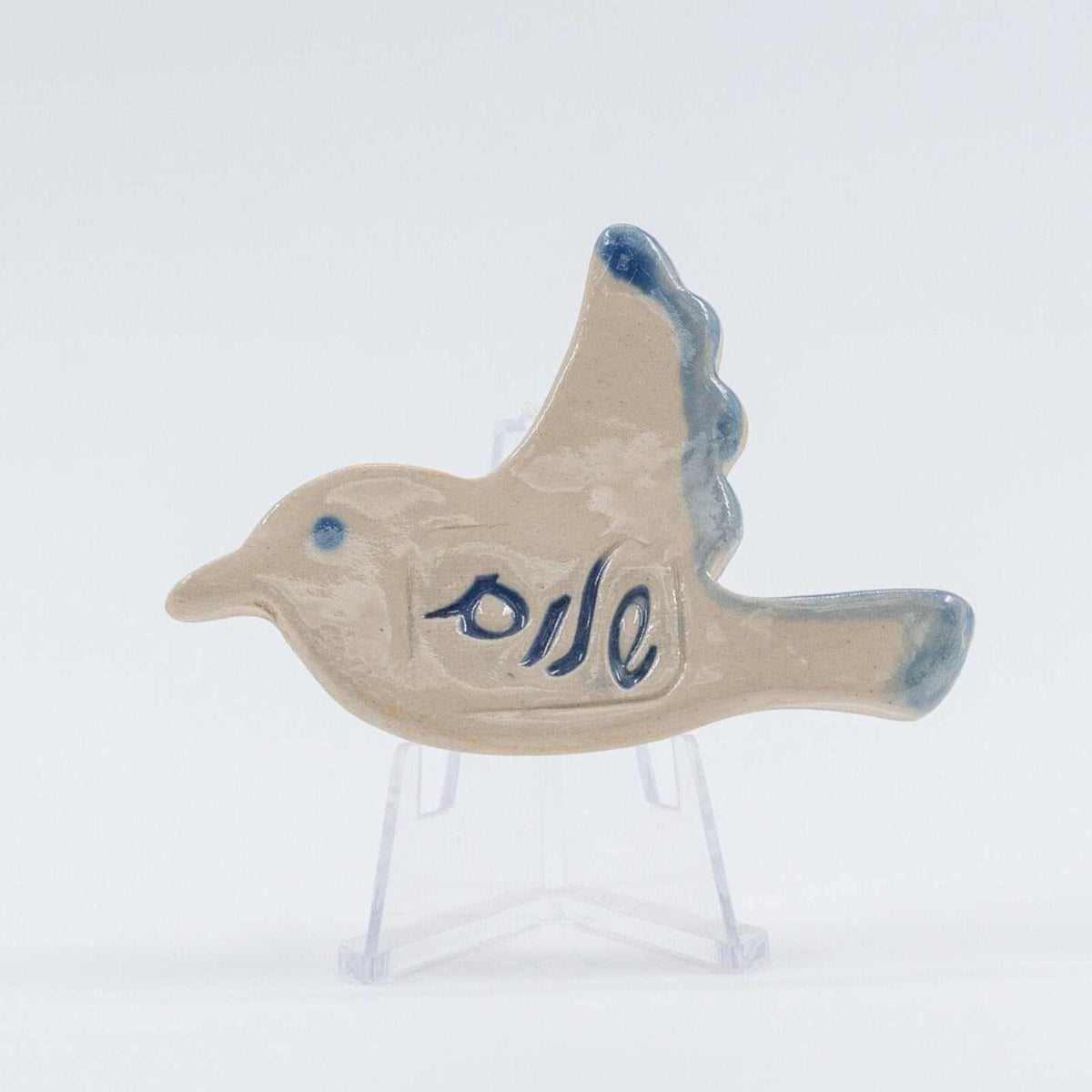 ADI Shalom Dove Magnet, beige ceramic dove with blue Hebrew lettering, a blue eye, and blue-tipped wings.