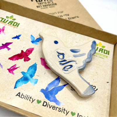 ADI Shalom Dove Magnet, cream ceramic dove with blue Hebrew lettering and a blue-edged wing detail.