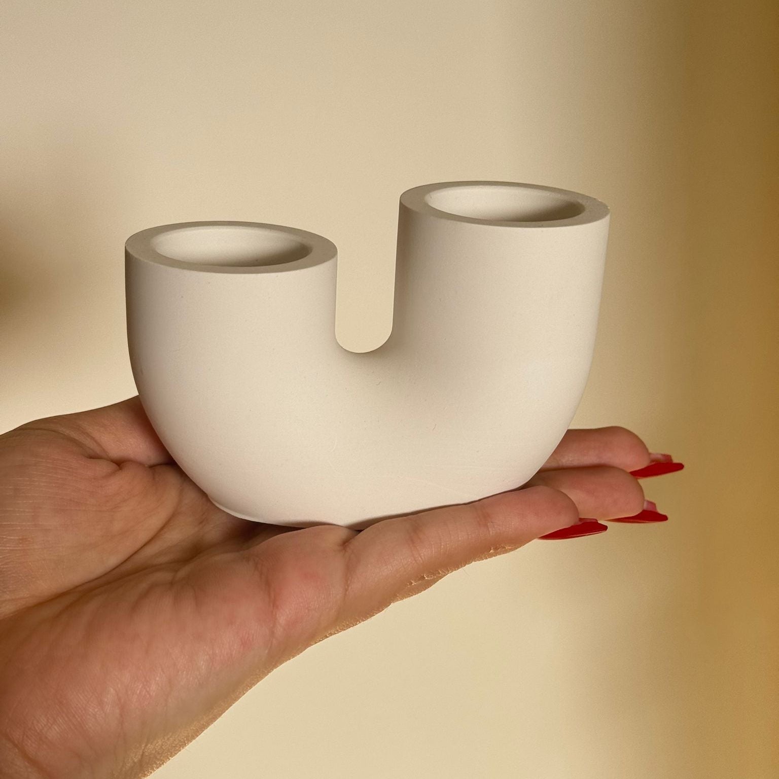 Minimalist white concrete candle holder with semicircle design and matching tall candles