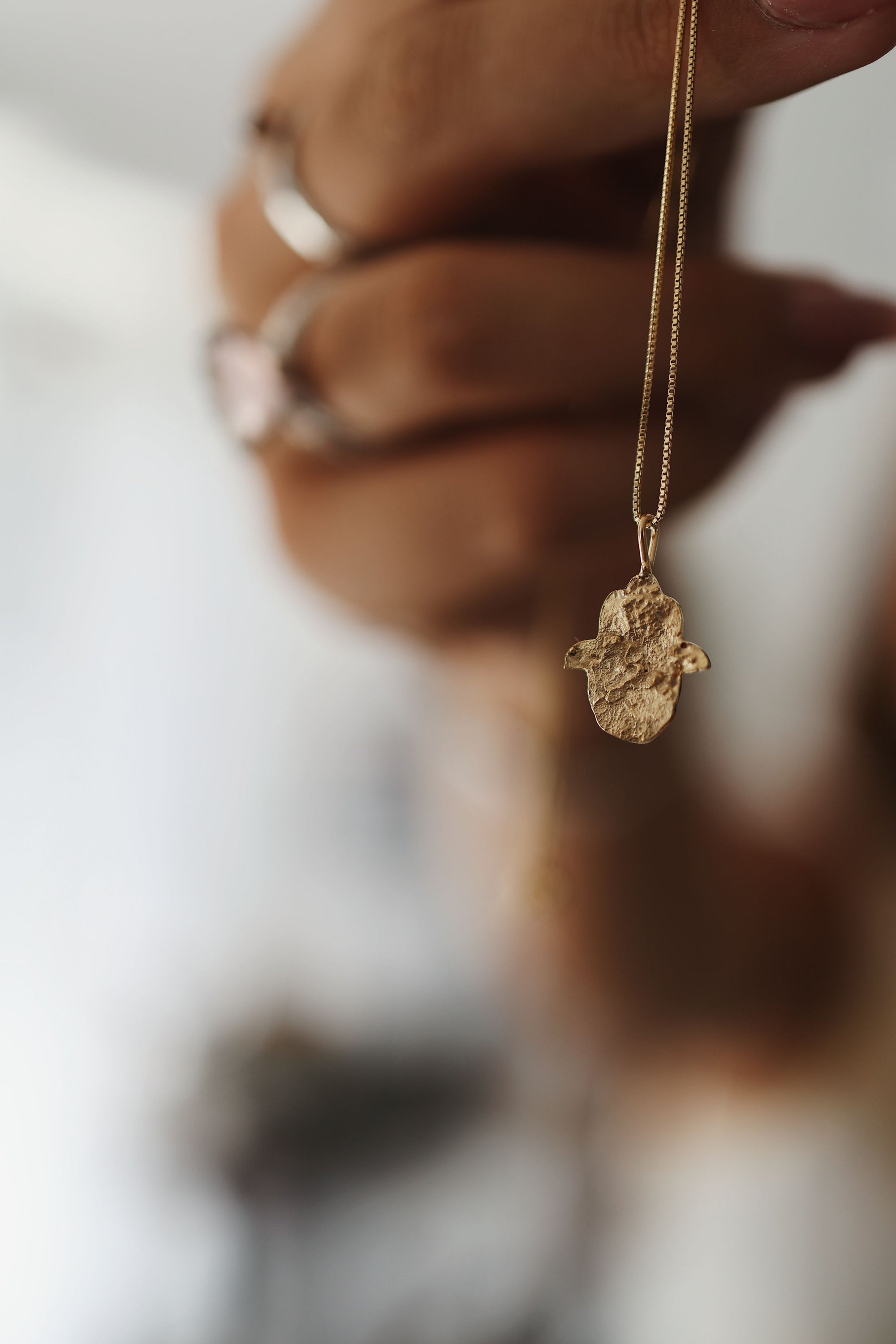 Sapir holding gold hamsa necklace