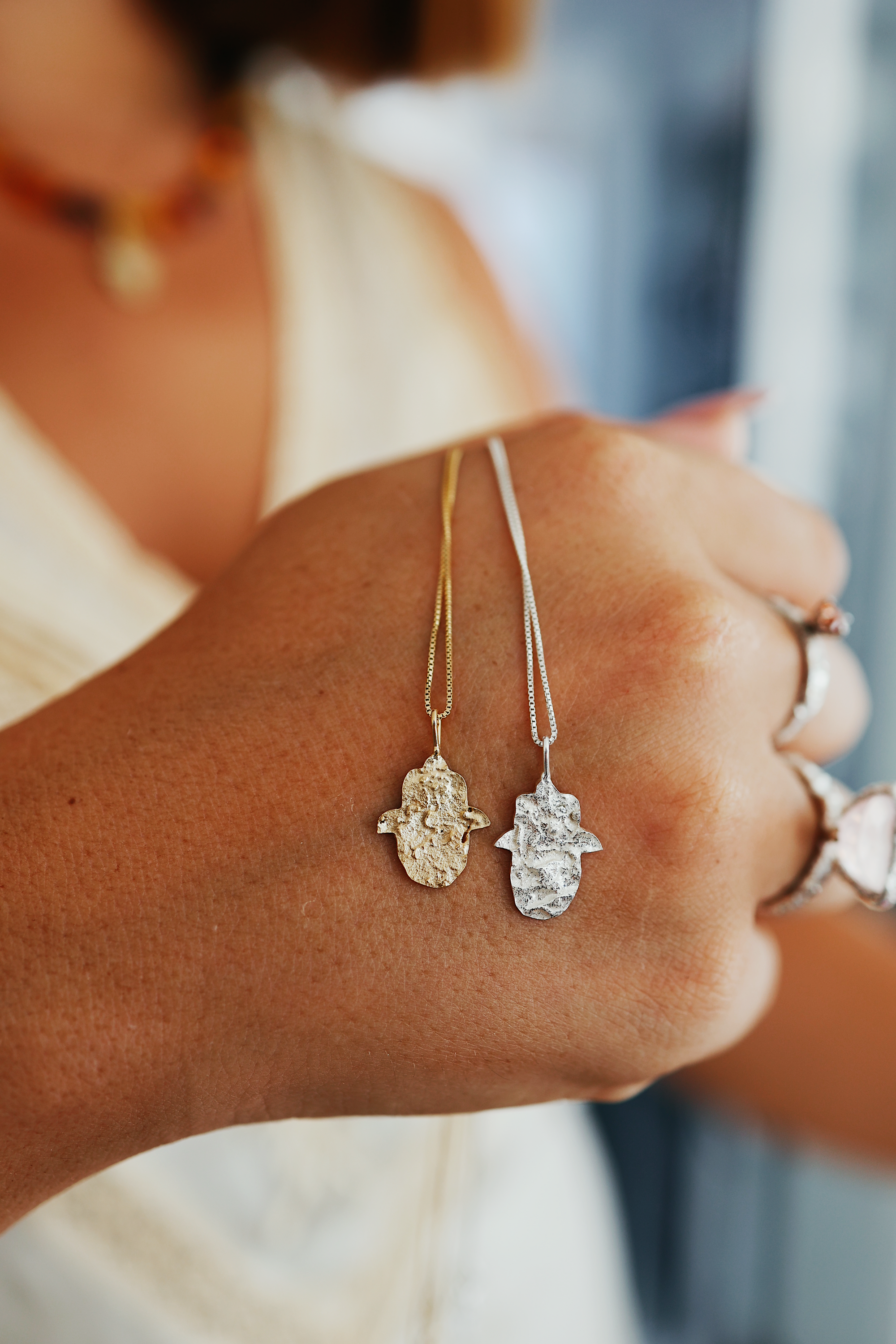 Sapir holding Gold and Silver Hamsa Necklaces