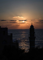 Sunset seascape with silhouetted lighthouse and buildings framed photographic print titled Anticipation Framed Print by Shye Klein