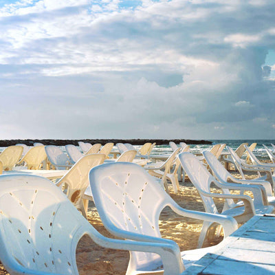 Anticipation — Framed Photography Print showing rows of empty white and pale yellow plastic beach chairs facing the sea.