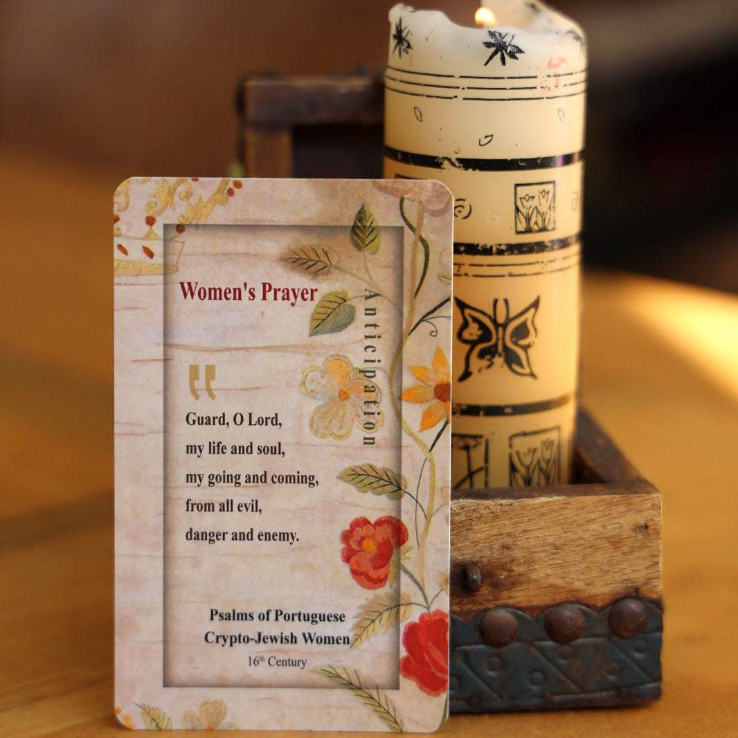Women's Prayer Card with floral design and protective prayer text beside a decorated candle on wooden table