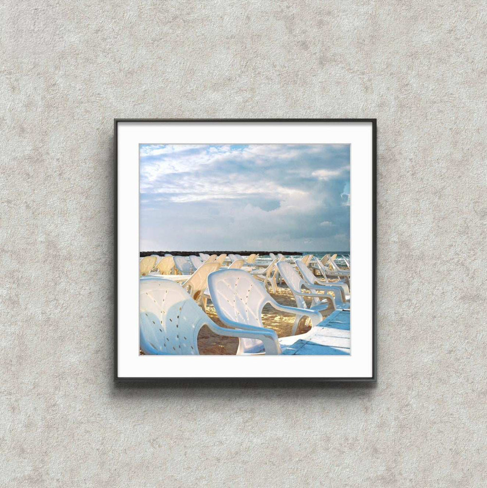 Anticipation framed print of empty white chairs on Charles Clore Beach, Tel Aviv, symbolizing stillness and hope.