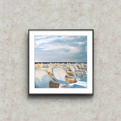 Anticipation — Framed Photography Print with a black frame, white mat, and photograph of empty white beach chairs under a blue sky.