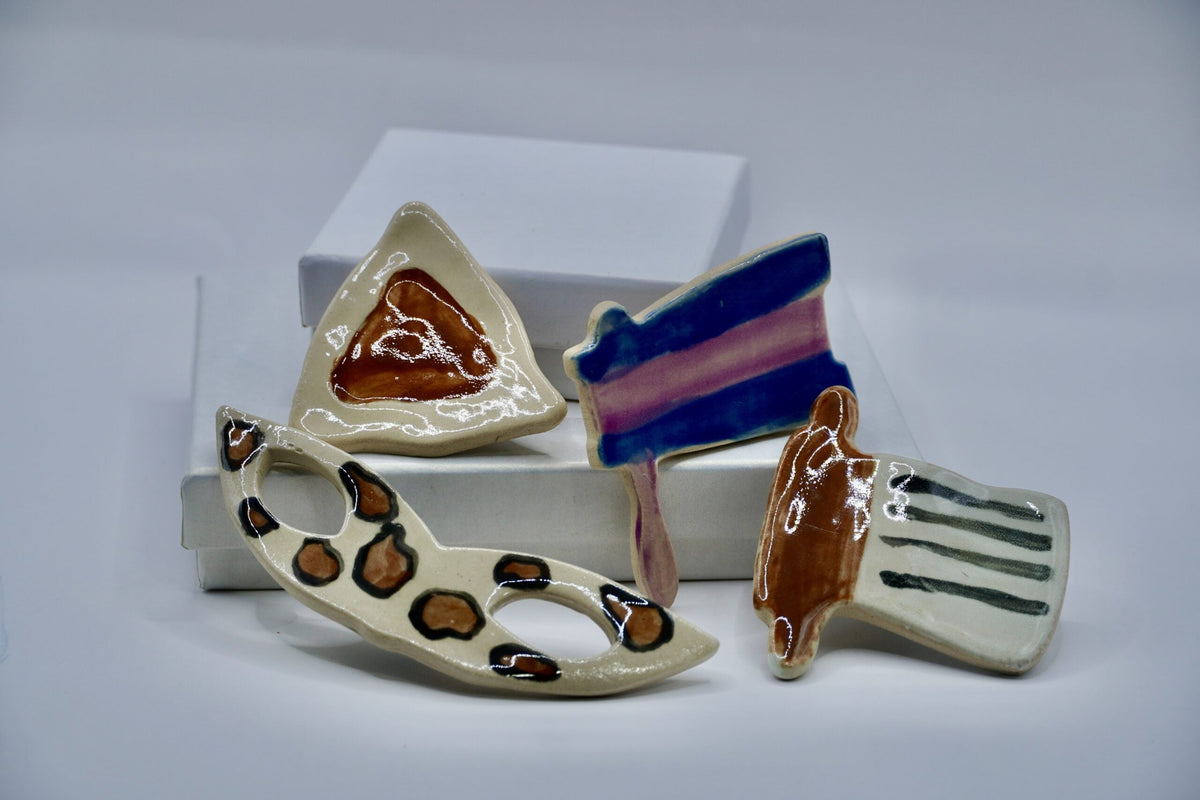 ADI Purim Magnet Set, four glossy ceramic magnets featuring a hamantaschen, spotted mask, striped grogger and megillah design.