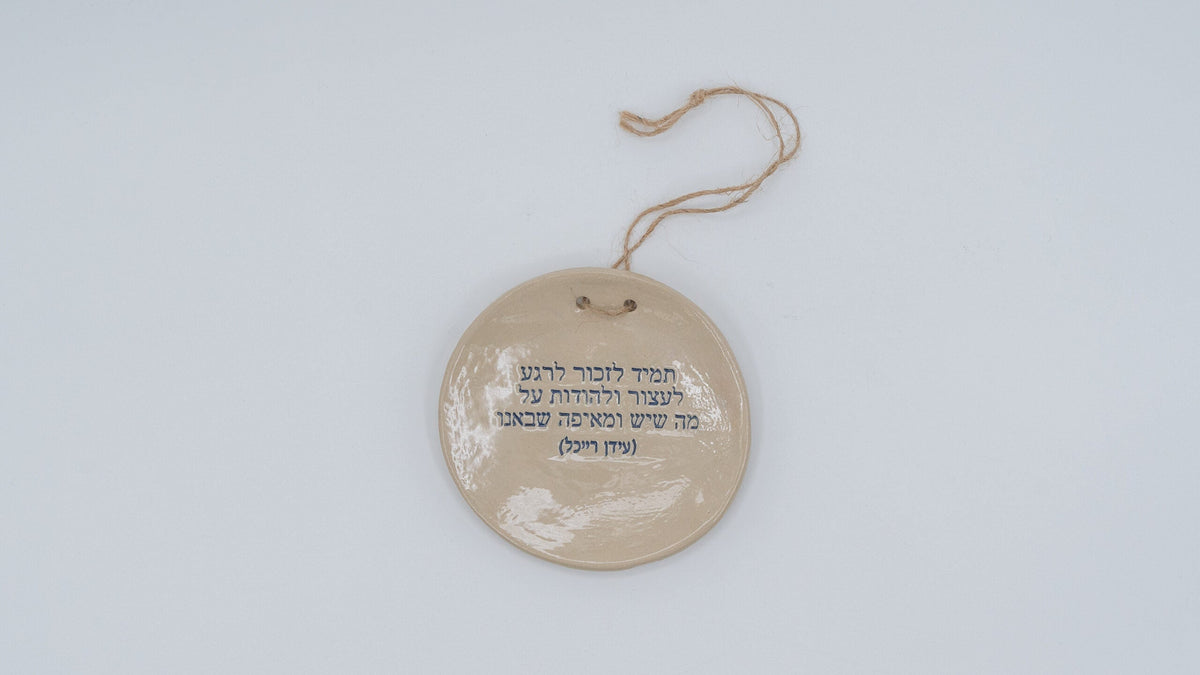 ADI Inspirational Quote Hanging Plate, round beige ceramic with a glossy finish, Hebrew text, and a hanging cord.