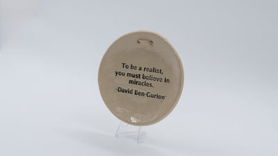ADI Inspirational Quote Hanging Plate, round beige ceramic with a black David Ben-Gurion quote and hanging hole