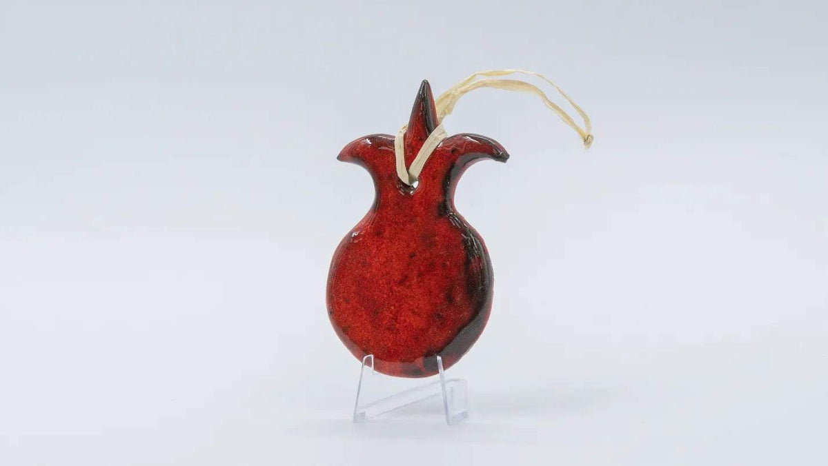ADI Pomegranate Wall Decoration in glossy red ceramic, with a dark speckled finish and gold hanging cord.