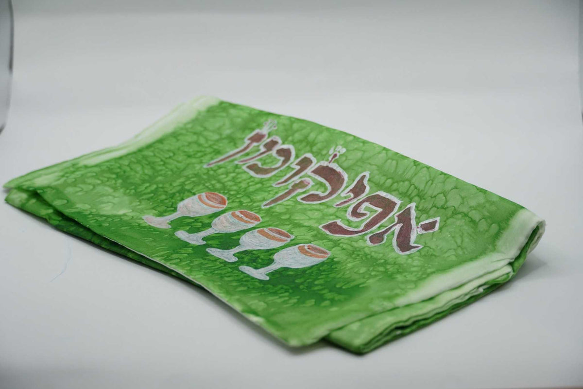 ADI Silk Afikoman Bag in bright green silk with a subtle swirling pattern, Hebrew lettering, and decorative Seder plate motifs.