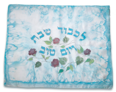 ADI Challah Cover in pale blue fabric with turquoise edging, Hebrew lettering, and a floral vine design in green and burgundy.