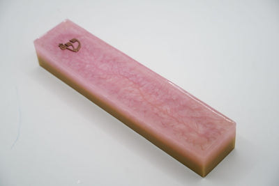 ADI Acrylic Mezuzah Case in pink acrylic with a marbled pattern and small gold-tone heart-shaped ornament near one end.