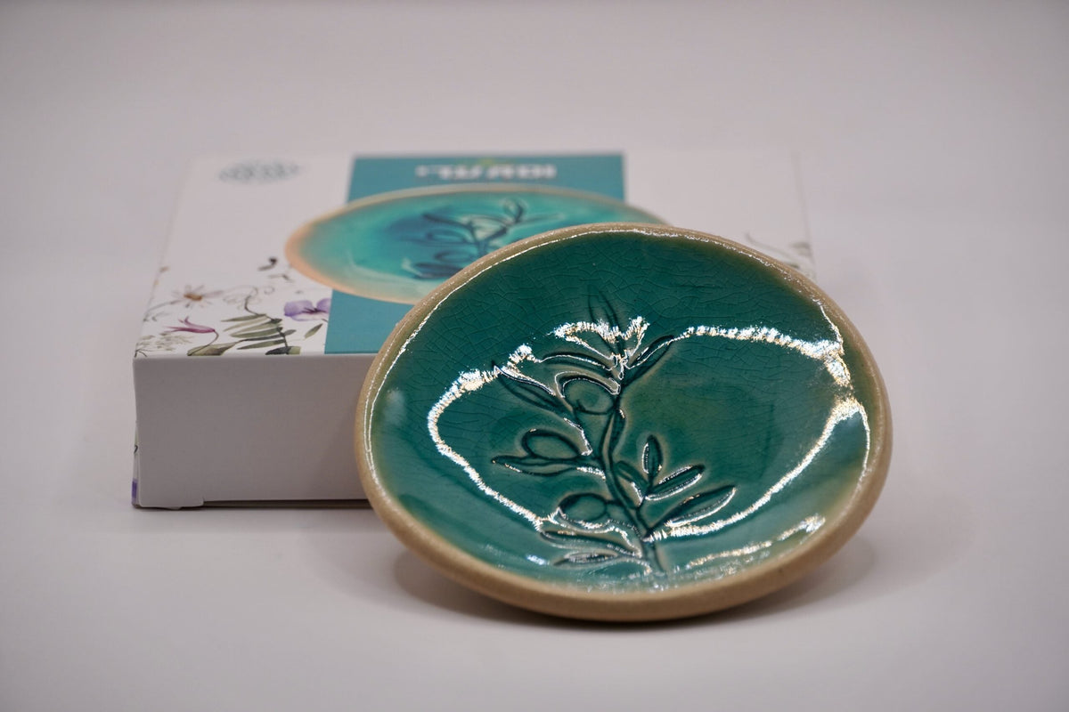 ADI Flower Plate, glossy teal ceramic with a raised botanical flower motif and a rounded tan rim.