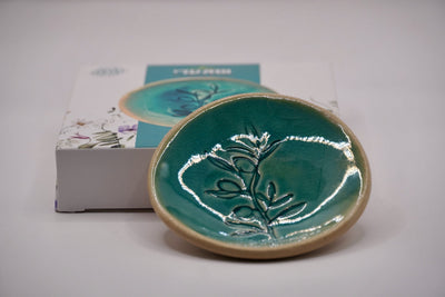 ADI Flower Plate, glossy teal ceramic with a raised botanical flower motif and a rounded tan rim.