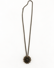 Nova Heaven Burning Man Necklace with a dark bronze-toned chain and sculptural, spiked sunburst pendant.
