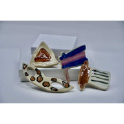 ADI Purim Magnet Set of four glossy ceramic magnets in a hamantaschen, mask, grogger, and megillah design.