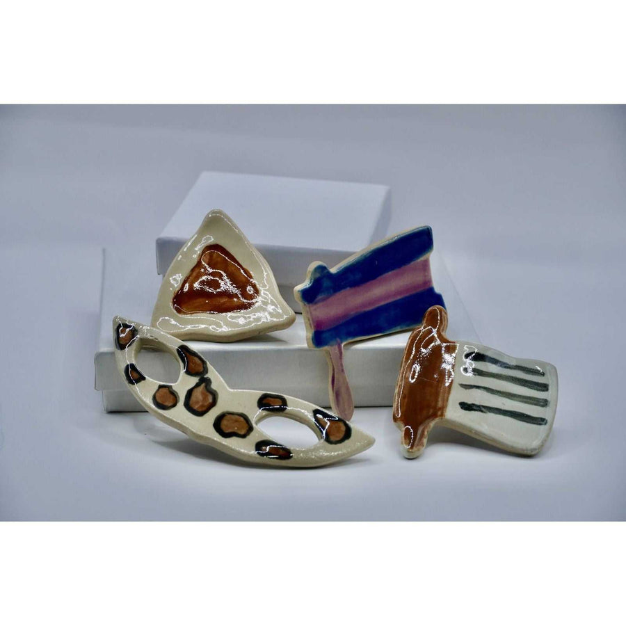 ADI Purim Magnet Set of four glossy ceramic magnets in a hamantaschen, mask, grogger, and megillah design.