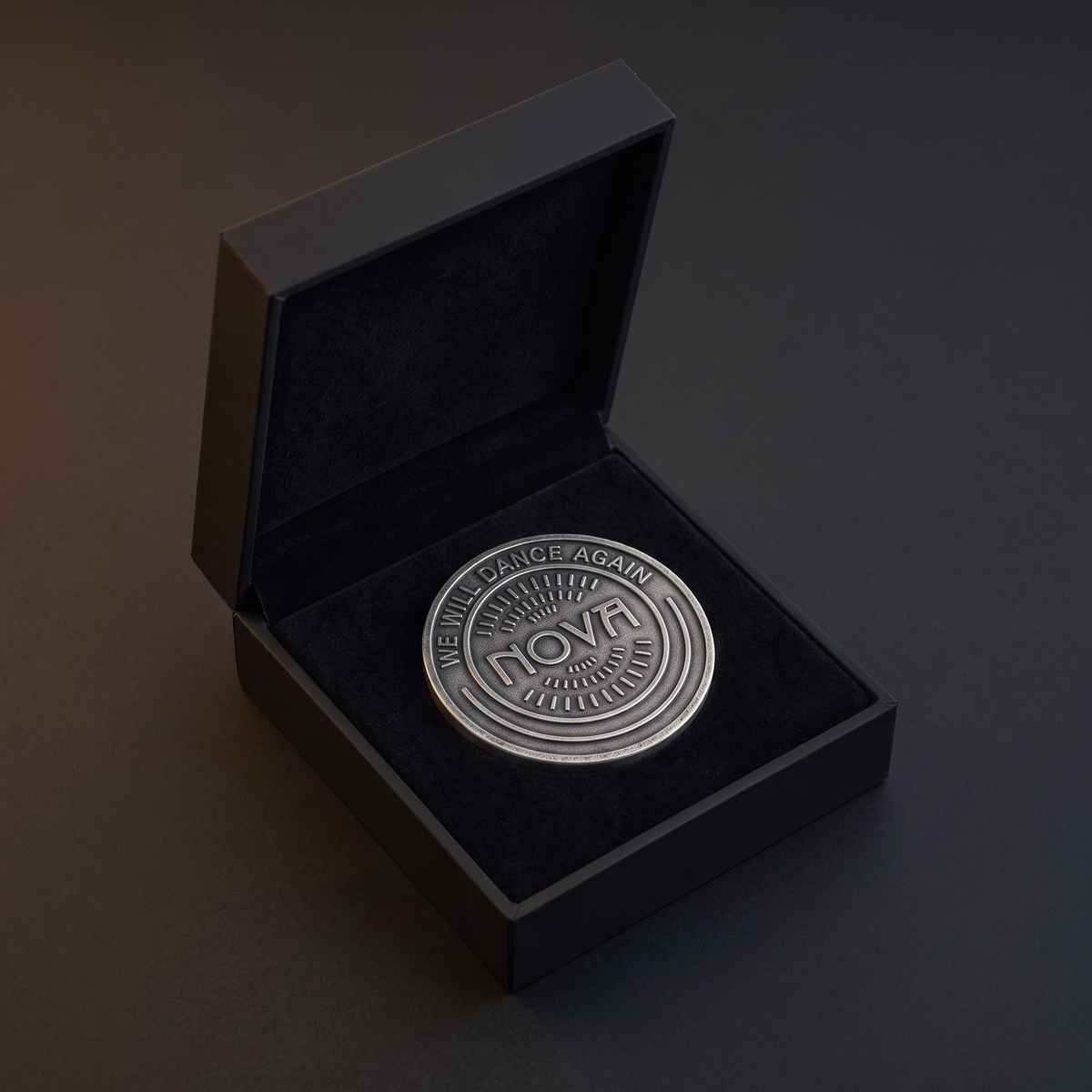 Nova 06:29 Exhibition commemorative coin in silver-tone metal, with concentric ridges and raised “NOVA” lettering in a black presentation case.