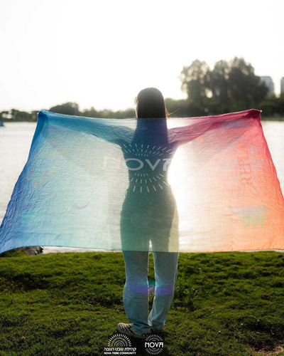 Nova Shawl in sheer multicolor cotton, with blue, turquoise, and pink gradients and a central Nova logo.