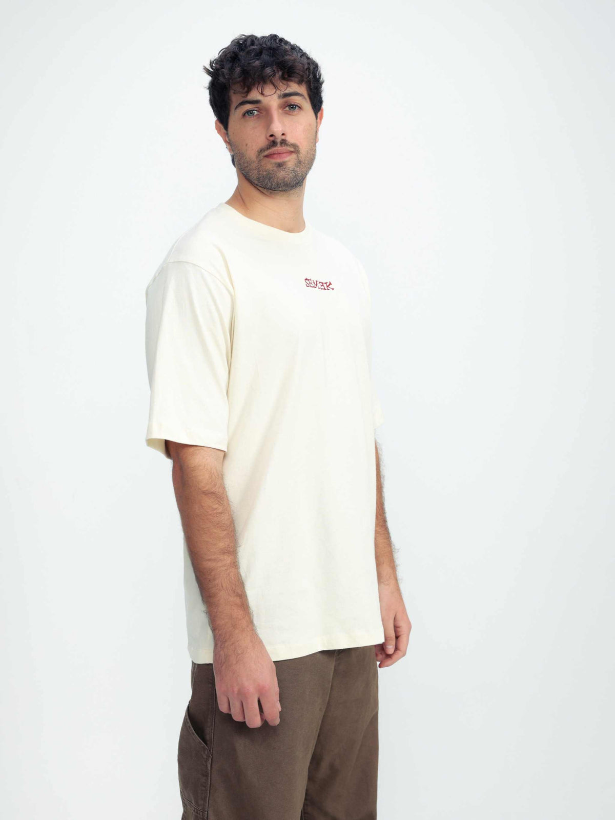 Omer Wenkert Heart T-Shirt, cream cotton with a small red chest logo and relaxed short sleeves; no heart graphic visible.