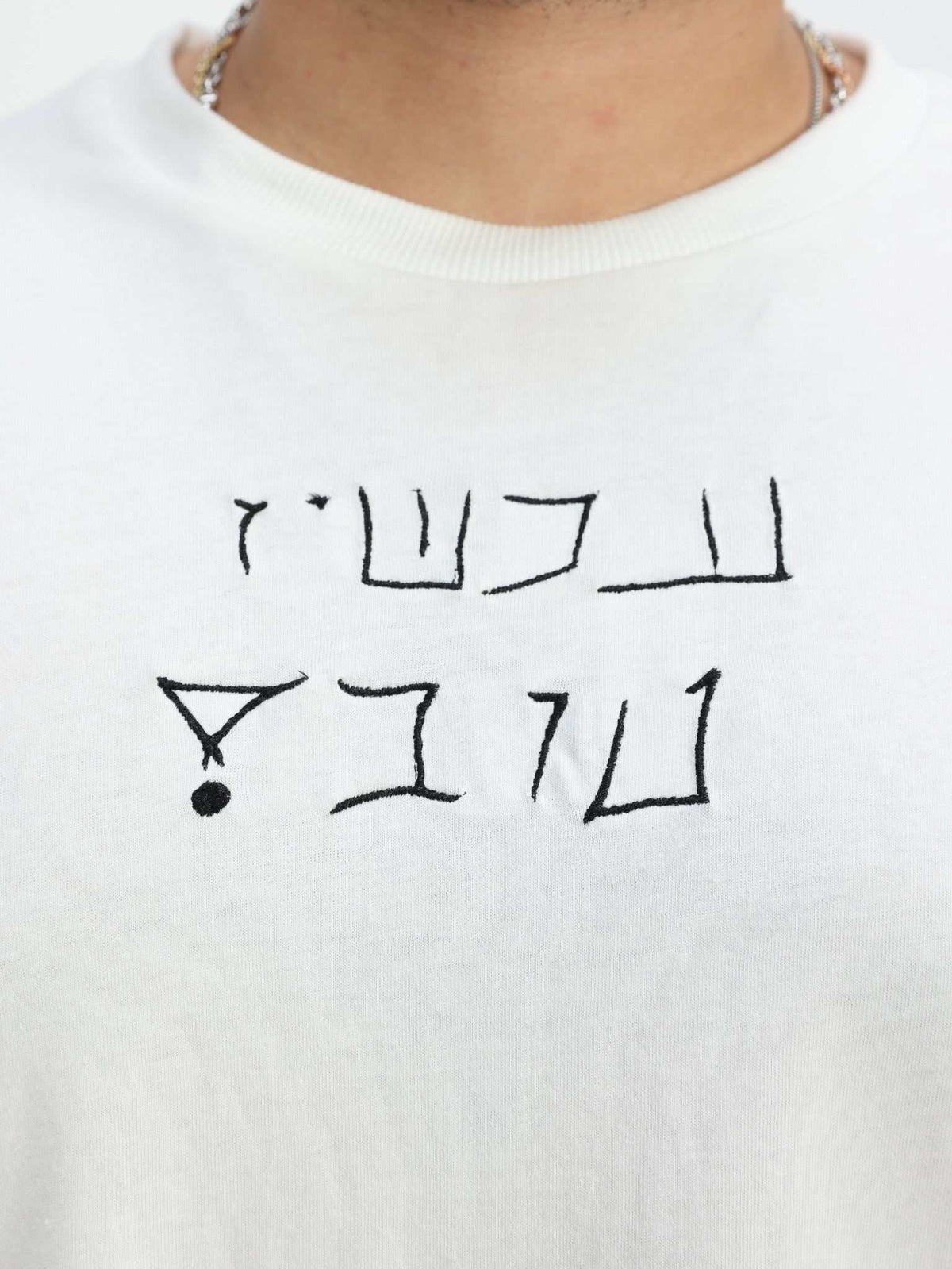 Omer Wenkert Now Is Good white cotton T-shirt with a simple black Hebrew message printed across the chest.