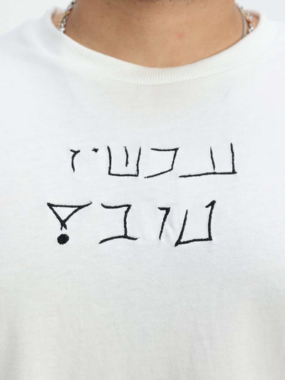 Omer Wenkert Now Is Good white cotton T-shirt with a simple black Hebrew message printed across the chest.